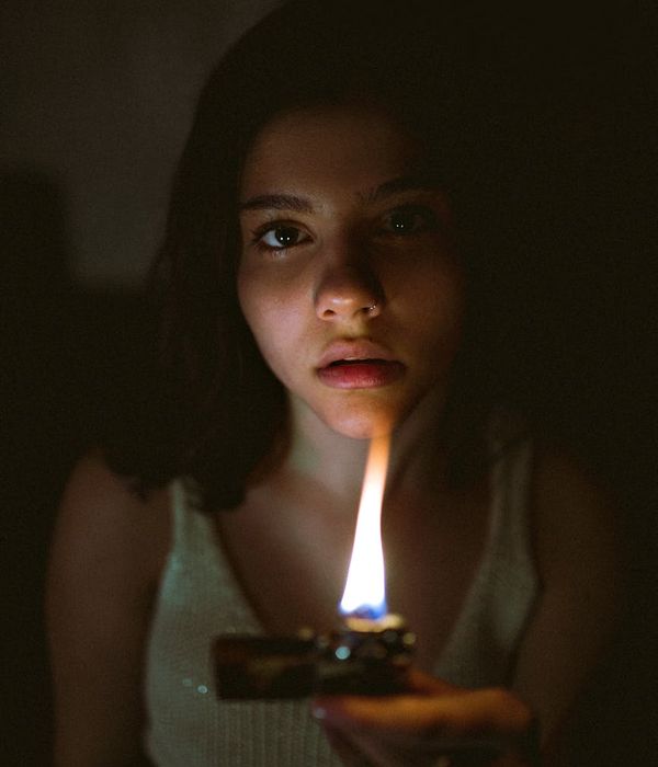 Woman in a calm, focused pose in a dimly lit room.